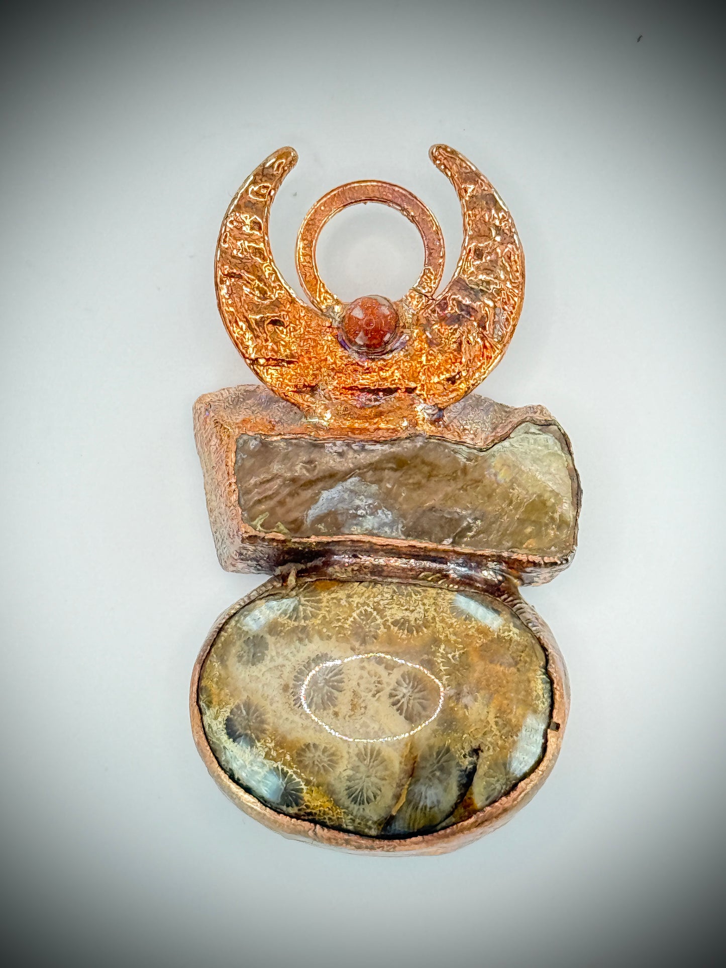 Handmade copper pendant with honey calcite, fossilized coral, goldstone, and an inverted crescent moon – earthy crystal jewellery for ambition and wisdom.