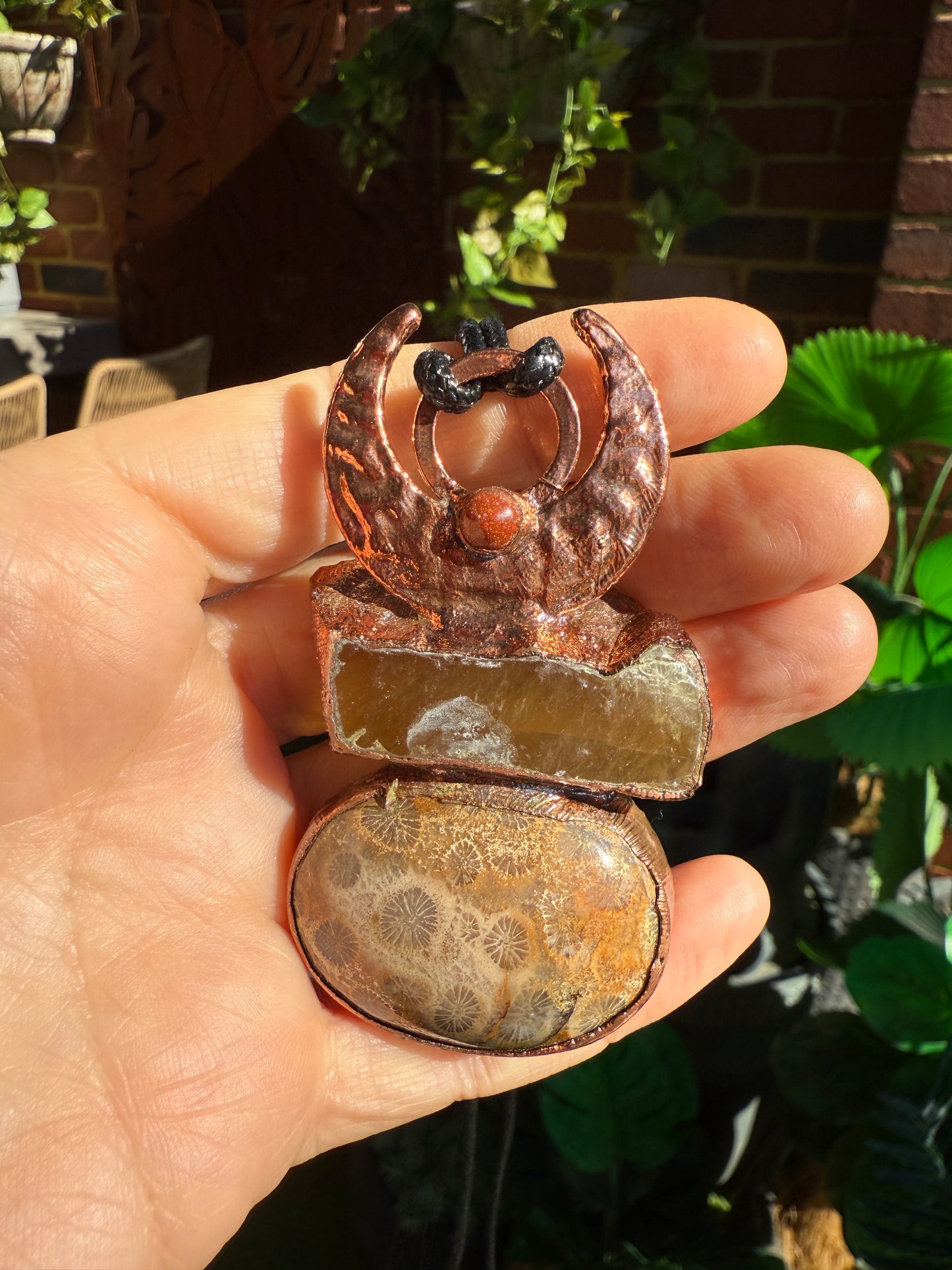 Handmade copper pendant with honey calcite, fossilized coral, goldstone, and an inverted crescent moon – earthy crystal jewellery for ambition and wisdom.